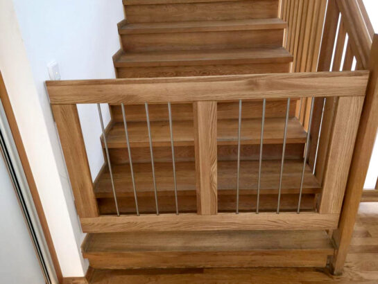 Maßgefertigtes Kinderschutzgitter aus massivem Eichenholz, passgenau montiert an einer Holztreppe von MM Doppelboden Martin Meyer.