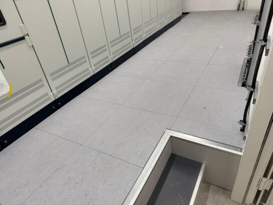 Montage eines grauen Doppelbodensystems mit Blick auf die offene Unterkonstruktion und die Schwerlaststützen von MM Doppelboden.