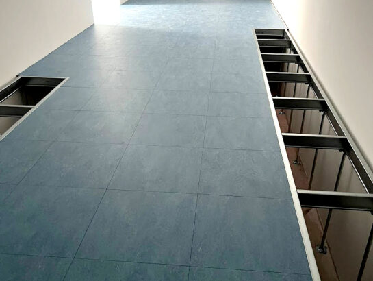 Weitläufiger, fertig verlegter Doppelboden in Blau-Grau mit sichtbarer Unterkonstruktion an den Seitenrändern von MM Doppelboden.