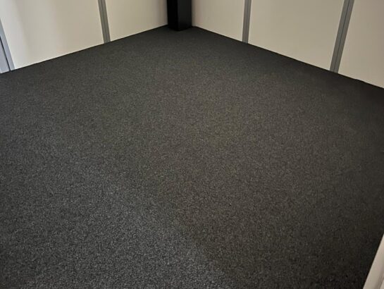 Hochwertiger, anthrazitfarbener Teppichbelag auf einem Doppelbodensystem in einem modernen Büroraum von MM Doppelboden.